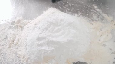 Doğal yumurta, metal masadaki taze buğday ununun üzerine düşer.