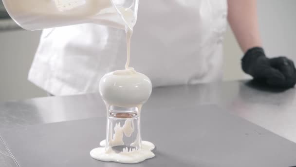 Konditor gießt weiße Sahne auf Kuchen am Metalltisch — Stockvideo