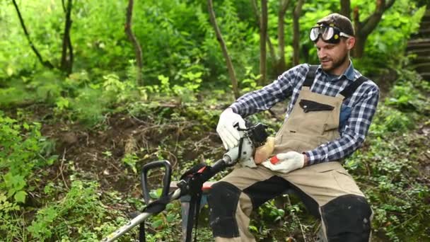 Man i rutig skjorta kontrollerar bensin tank trimmer — Stockvideo