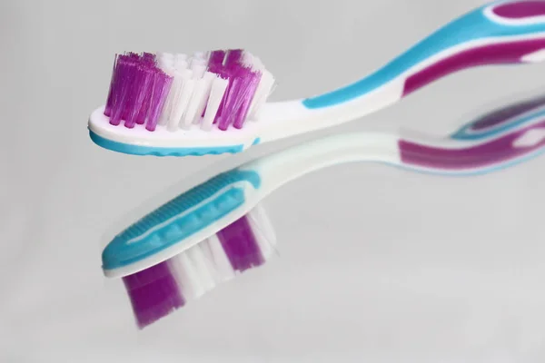 Toothbrushes and toothpaste on a mirror shelf. Oral hygiene products. — Stock Photo, Image