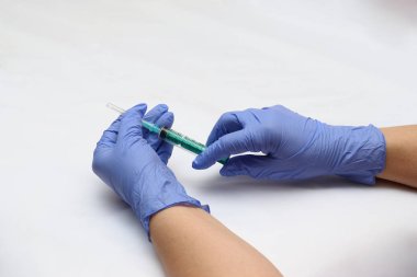 Eldiven el üstünde mavi. Bir iğne ile şırınga. İlacın enjeksiyon için hazırlık.