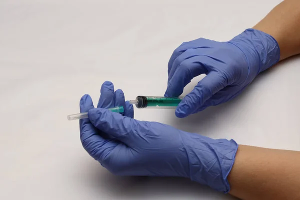Luvas azuis à mão. Seringa com uma agulha. Preparação para a injeção do medicamento . — Fotografia de Stock