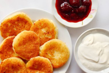 Güzel kokulu kırmızı altın kahverengi bir kabuk ile taze çilek reçeli ve ekşi krema boru sıcak şurubu curds(cheesecake) pişmiş.