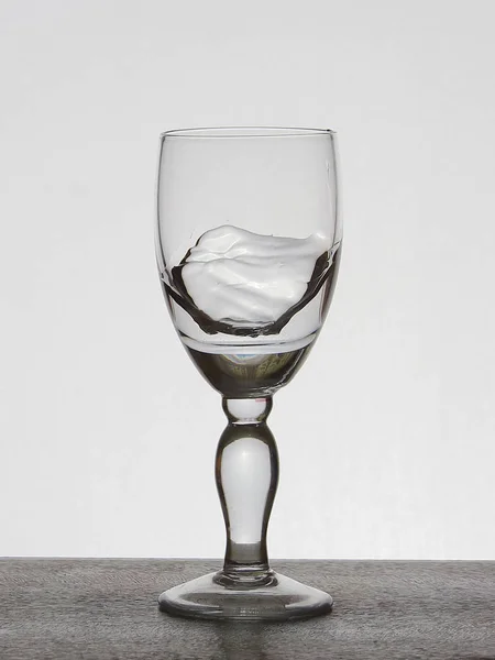 Sprühflüssigkeit (klares Wasser, Rotwein) aus einem Glasbecher. — Stockfoto