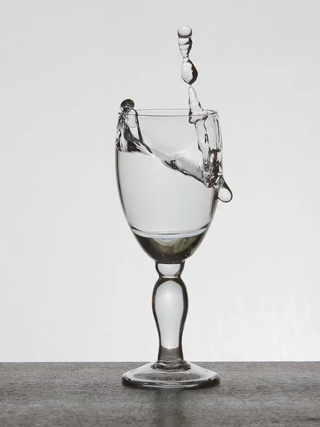 Spray liquid (clear water, red wine) from a glass goblet. — Stock Photo, Image