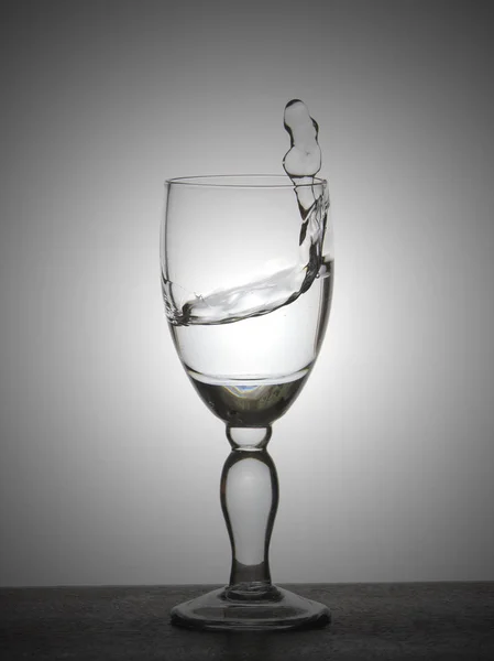 Pulvérisation liquide (eau claire, vin rouge) à partir d'un gobelet en verre . — Photo