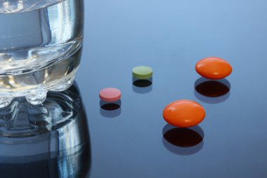 Parlak renkli tablet, hap, kapsül bir cam masa üzerinde.