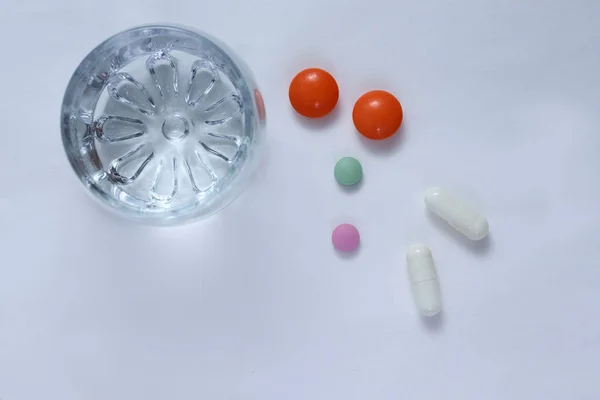 Bright colored tablets, pills, capsules on a glass table.