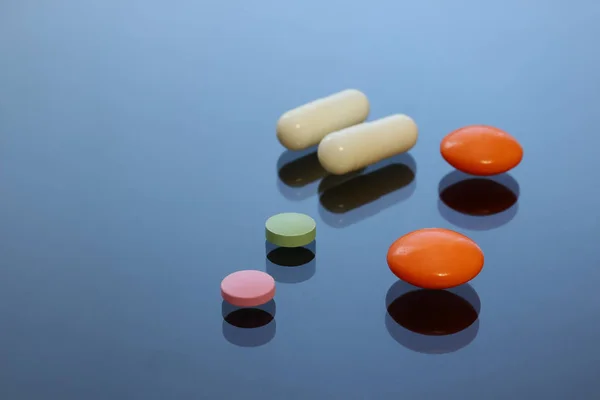 Comprimidos coloridos brilhantes, comprimidos, cápsulas em uma mesa de vidro . — Fotografia de Stock