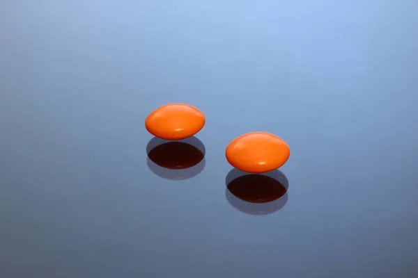 Bright colored tablets, pills, capsules on a glass table.