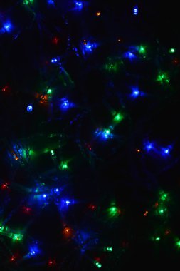 Karanlıkta renkli ışıklar (çelenk). Bokeh efekti şenlikli aydınlatma.