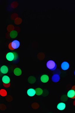 Karanlıkta renkli ışıklar (çelenk). Bokeh efekti şenlikli aydınlatma.