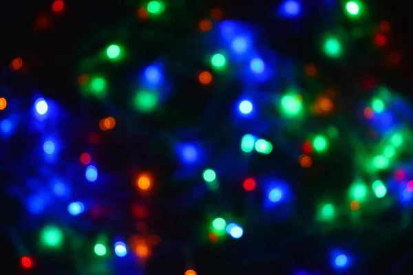 Kolorowe światła (Garland) w ciemności. Efekt bokeh Świąteczna iluminacja. — Zdjęcie stockowe