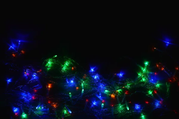Gekleurde lichten (slinger) in het donker. Bokeh effect feestelijke verlichting. — Stockfoto