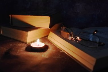 Samimi bir ortamda Aydınlatılmış mumlar, eski kitaplar, zaman zaman sararmış, örme sarı iplik gözlük.