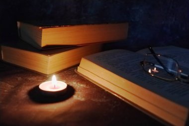 Samimi bir ortamda Aydınlatılmış mumlar, eski kitaplar, zaman zaman sararmış, örme sarı iplik gözlük.
