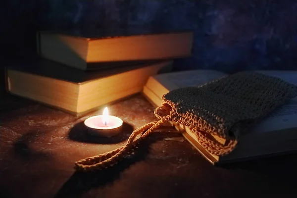 Lighted candles in an intimate setting, old books, yellowed from time to time, glasses in a knitted yellow thread. — Stock Photo, Image