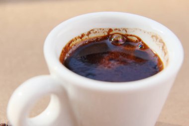 Yükselen güneşin ışınlarında bir karton yüzeye dağılmış aromatik kavrulmuş kahve taneleri.