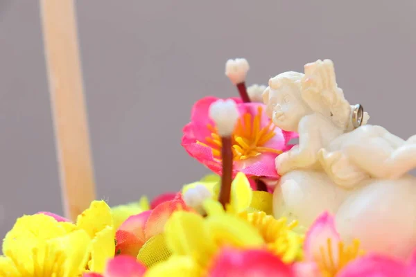 Anjo branco em um coração em um buquê de flores artificiais em um cesto . — Fotografia de Stock