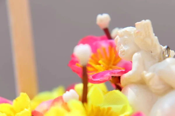 Anjo branco em um coração em um buquê de flores artificiais em um cesto . — Fotografia de Stock