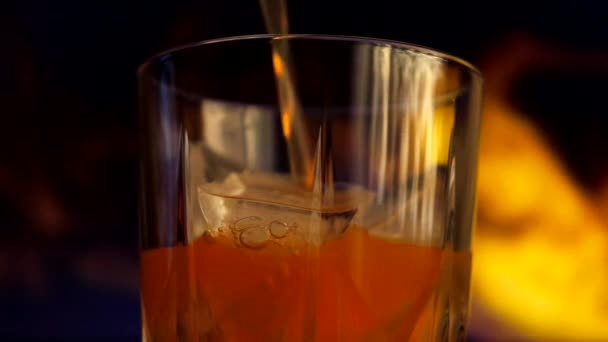黄色とオレンジの甘いマルチフルーツジュースは 氷のキューブとガラスに注がれます 色付きの煙を背景にジュースを塗ったグラス — ストック動画