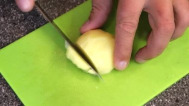 Gri granit taklidi ile bir tezgah üzerinde yeşil bir kesme tahtası üzerinde küpler halinde patates kesme.