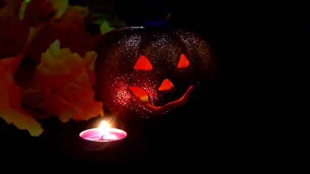 Attributi vacanze autunnali di Halloween. Una zucca di plastica cava con una smorfia "sinistra" incisa e una candela (LED colorati) all'interno . — Video Stock