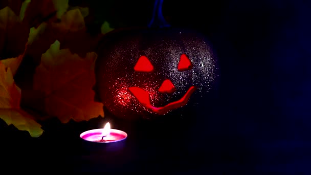 Halloween-Herbstferien. ein hohler Plastikkürbis mit einer "finsteren" Fratze darauf und einer Kerze (farbige LEDs) im Inneren. — Stockvideo