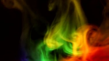 Karanlık bir zemin üzerinde kıvrımlı duman kabarcıkları, farklı renklerde ışık tarafından aydınlatılıyor..