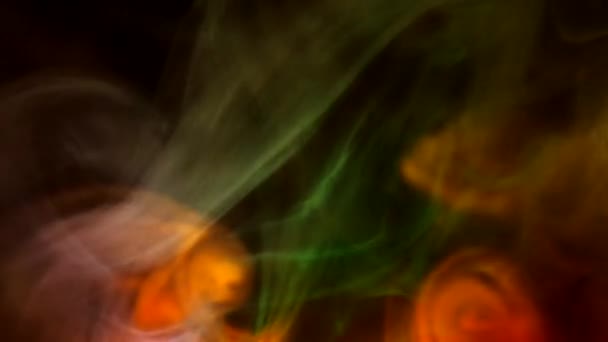 Lockigt krypande puffar av rök på en mörk bakgrund, upplyst av ljus med olika färger. — Stockvideo
