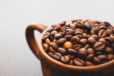 Kahverengi seramik bardak ve boyalı desenler. Kahve fincanı masanın üstünde. Kahverengi kavrulmuş kahve taneleriyle dolu bir fincan. Kokulu kahve taneleri..