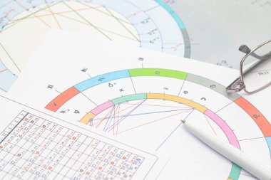 Modern bir astrologun iş yerinin büyüsü. Astrolojik çizelgeler masaya saçılmış, tablolar, çizelgeler, şemalar. Gezegenlerin, evlerin, bakış açılarının simgeleri.