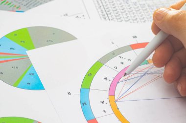 Modern bir astrologun iş yerinin büyüsü. Astrolojik çizelgeler masaya saçılmış, tablolar, çizelgeler, şemalar. Gezegenlerin, evlerin, bakış açılarının simgeleri.