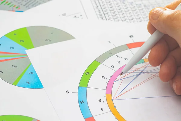 Modern bir astrologun iş yerinin büyüsü. Astrolojik çizelgeler masaya saçılmış, tablolar, çizelgeler, şemalar. Gezegenlerin, evlerin, bakış açılarının simgeleri.