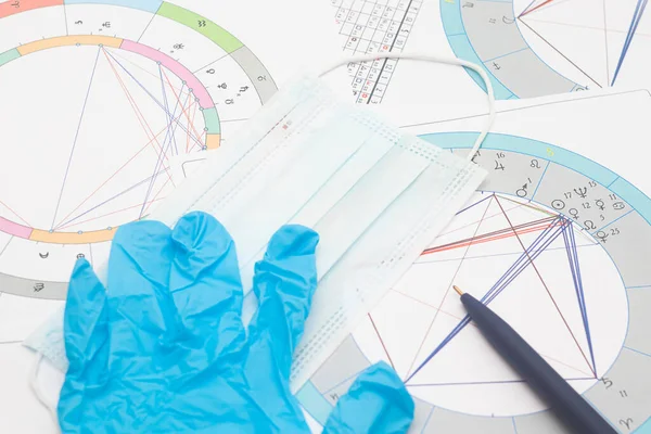 New pandemic realities of the work of a modern astrologer, the workplace of the predictor of a foggy future in the context of the COVID-19 pandemic. Astrological charts, tables, diagrams scattered in a mess around the table. Among others, personal pr