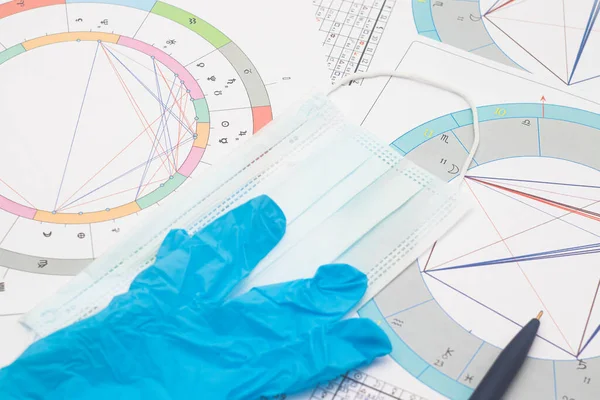 New pandemic realities of the work of a modern astrologer, the workplace of the predictor of a foggy future in the context of the COVID-19 pandemic. Astrological charts, tables, diagrams scattered in a mess around the table. Among others, personal pr