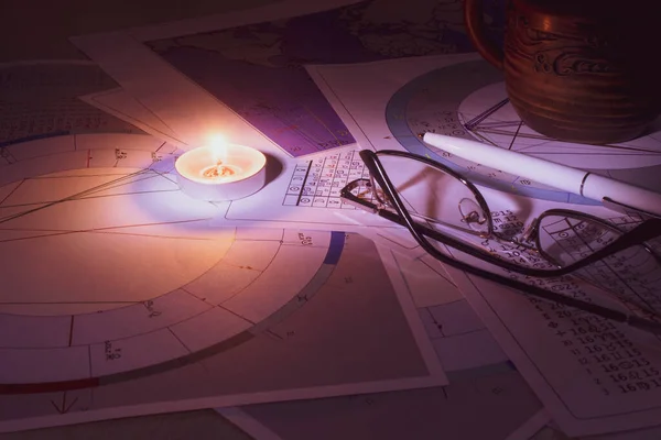 Modern bir astrologun işyeri. Bir astrologun aksesuarları. Bilgisayar astrolojik haritaları ve tabloların çıktıları. Astrolojik semboller ve işaretler.