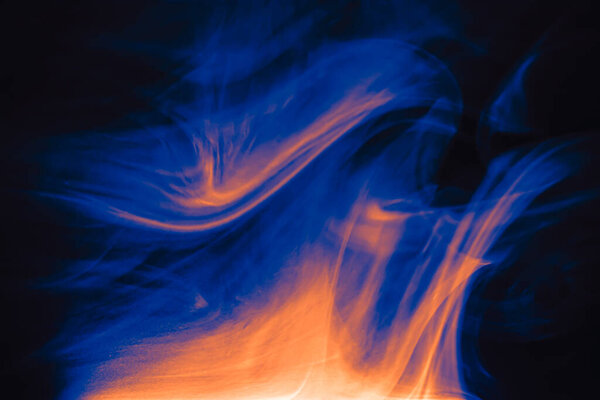 Clouds of colored flowing smoke on a dark background. Smoky extravaganza. Flying smoky vague fantasies.
