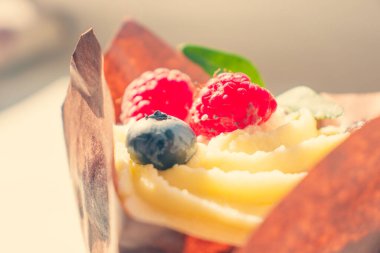 Ahududu ve yaban mersinli parlak tatlı meyveli cheesecake. Çevre dostu sarı kâğıt kağıdına sarılmış peynirli kek..