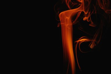 Siyah arka planda turuncu duman. Renkli duman. Duman turuncu ışıkla aydınlatılıyor. Tuhaf heceleyici alevler.