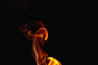 Siyah arka planda turuncu duman. Renkli duman. Duman turuncu ışıkla aydınlatılıyor. Tuhaf heceleyici alevler.