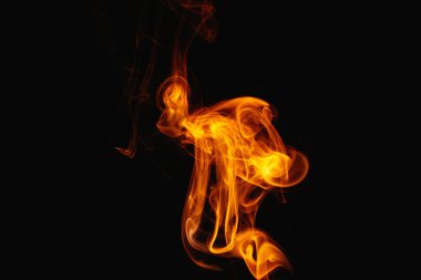 Siyah arka planda turuncu duman. Renkli duman. Duman turuncu ışıkla aydınlatılıyor. Tuhaf heceleyici alevler.