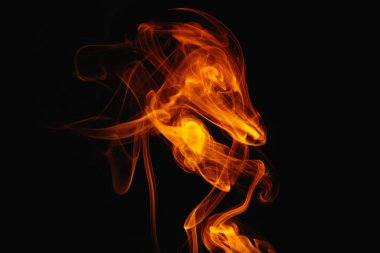 Siyah arka planda turuncu duman. Renkli duman. Duman turuncu ışıkla aydınlatılıyor. Tuhaf heceleyici alevler.