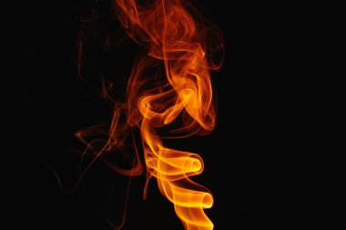 Siyah arka planda turuncu duman. Renkli duman. Duman turuncu ışıkla aydınlatılıyor. Tuhaf heceleyici alevler.