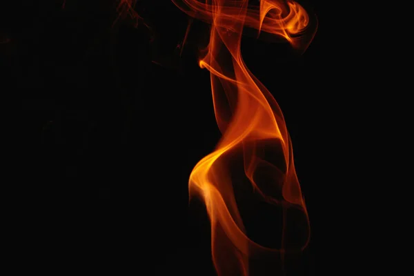 Orange smoke on a black background. Colored smoke. Smoke illuminated by orange light. Bizarre spellbinding flames.