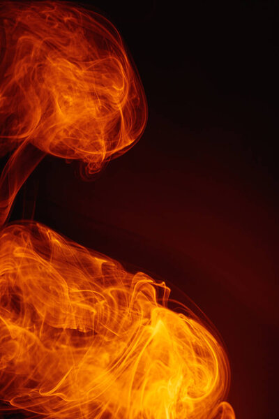 Orange smoke on a dark background. Intricate swirls of colored smoke. An abstract imitation of night flames.