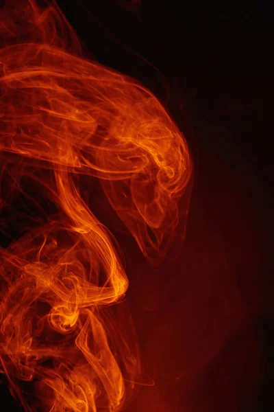 어두운 배경에는 주황색 연기가 피어 있다. 세게 휘몰아치는 색깔의 연기. — 스톡 사진