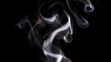 Yanan bir tütsü çubuğundan çıkan duman. Karanlık bir arka planda tuhaf bukleler.