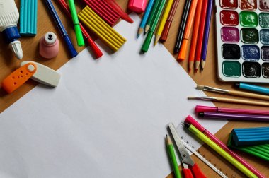 Boş kağıt ile masaya üst görünüm. Metin alanı ile okul konseptine geri dönün. Boya fırçaları, kalem ve plastikine sahip renk boyaları. Çocuk boyama konsepti. Çocuk sanatı.