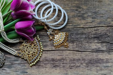 Dans için Hint süslemeleri: bilezik, kolye. Eski rustik ahşap arka planda mor ultraviyole lale.